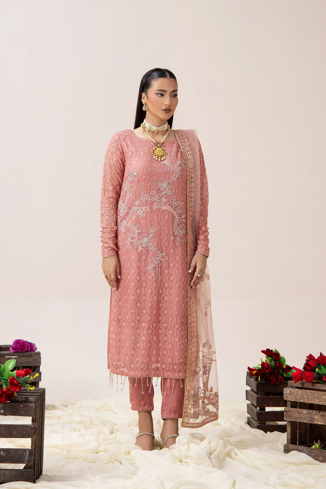 Elegant pink embroidered Pakistani suit with floral motifs, paired with matching dupatta and pants, styled for festive occasions.