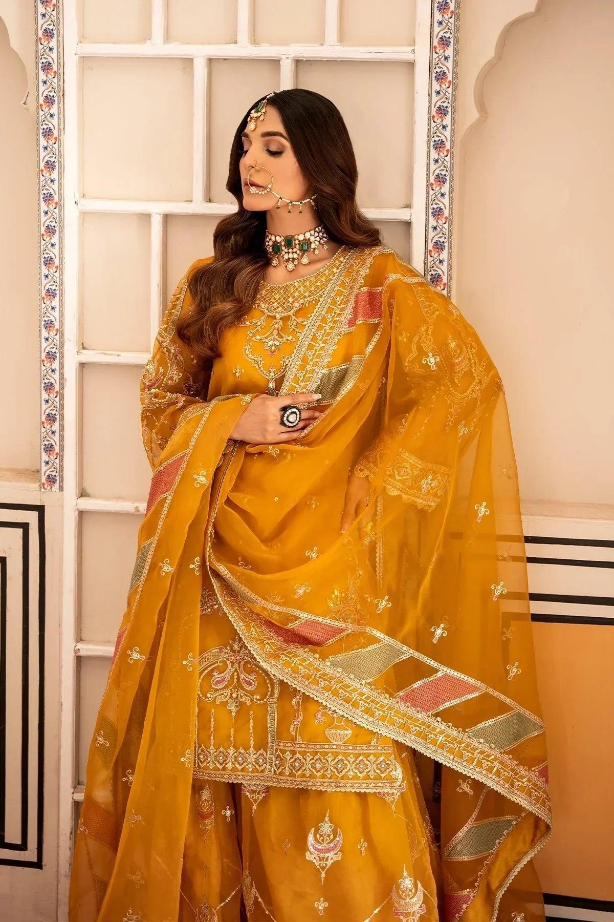 Elegant mustard yellow embroidered Pakistani dress with intricate gold detailing and traditional jewelry