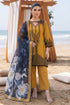 Mustard embroidered Pakistani suit with blue floral dupatta, beach setting