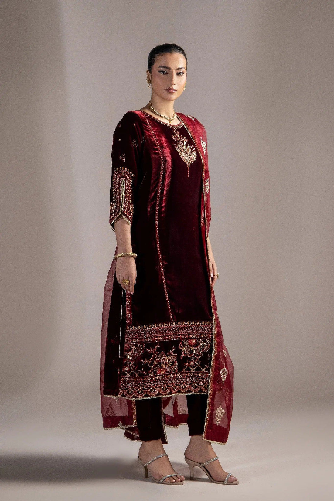 Elegant maroon velvet embroidered dress with gold detailing, perfect for formal occasions in Pakistan.