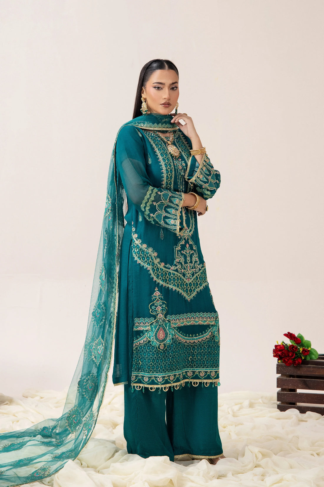 Emerald green embroidered Pakistani suit with gold detailing, matching dupatta, and statement jewelry for festive occasions.